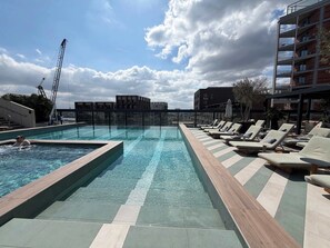 Ein Dachpool mit Liegestühlen und Blick auf die Stadt.