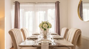 A dining room with a marble table, six chairs, a vase of white flowers, and sheer curtains. - MAGICAL MARBLE 3 BEDROOM KNIGHTSBRIDGE GOLDEN APARTMENT WITH BALCONY (Greater London)