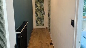 En gang med trægulv, en radiator og en dør med bladmotiv.