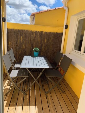 Eine Terrasse mit Tisch und Stühlen, einem Blumentopf und einer gelben Wand.