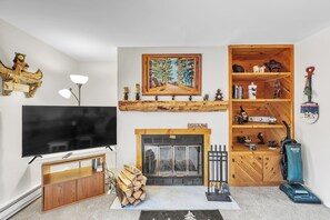 Ein Wohnzimmer mit Fernseher, Kamin, Holzregalen und einem Gemälde.