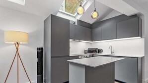 A modern kitchen with grey cabinetry, a central island, and pendant lighting. - VOLCANIC HOT TUB EXPERIENCE Central London 2BR Lagoon, Memories Await for 6 (Greater London)