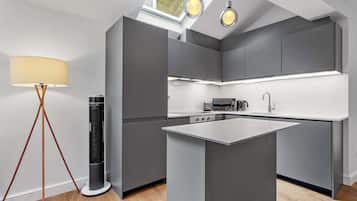 Une cuisine moderne avec des meubles de couleur grise, un îlot central et des luminaires suspendus.