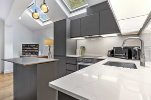 A modern kitchen with a central island, built-in appliances, and a skylight. - VOLCANIC HOT TUB EXPERIENCE Central London 2BR Lagoon, Memories Await for 6 (Greater London)