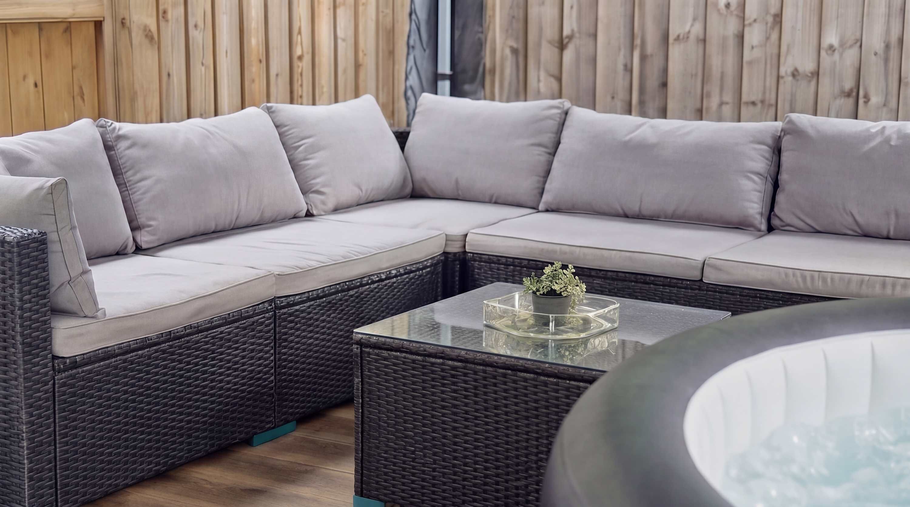 Un canapé modulable avec des coussins, une table basse en verre agrémentée d’une plante et un sol en osier.