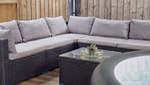 A sectional sofa with cushions, a glass coffee table with a plant, and a wicker floor. - VOLCANIC HOT TUB EXPERIENCE Central London 2BR Lagoon, Memories Await for 6 (Greater London)