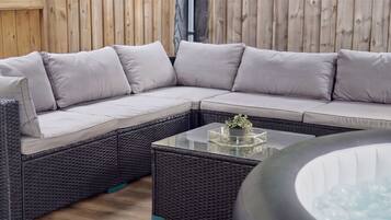 Un canapé modulable avec des coussins, une table basse en verre agrémentée d’une plante et un sol en osier.
