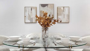 A dining table with a glass top surrounded by white chairs, set with white plates, bowls, and cutlery. - VOLCANIC HOT TUB EXPERIENCE Central London 2BR Lagoon, Memories Await for 6 (Greater London)