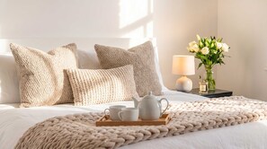 A neatly made bed with a beige knitted blanket, a wooden tray with a teapot and cups, and a vase with white flowers on a bedside table. - Shard View on Terrace 4BR Rare London Station Stay, Close to London Eye, 2 Min walk From Station, Cinematic Scenes for 10 (Greater London)