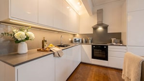 Una cocina moderna con armarios blancos, horno empotrado, microondas y campana extractora de acero inoxidable.