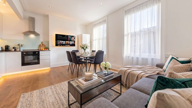 Uma sala de estar moderna com sofá, mesa de centro e área de jantar com cadeiras.