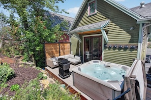 Ein Haus mit Whirlpool, Sitzgelegenheit im Freien und einer überdachten Terrasse.