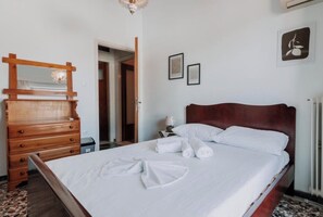 A bedroom with a wooden dresser, a bed with white linens, and a framed picture on the wall. - Altana Vista Argolis - Panoramic Castle View (Argos)