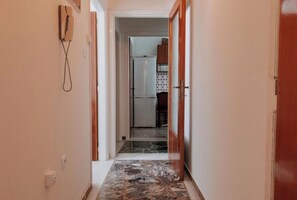 A narrow hallway with a marble floor leading to a kitchen area with a refrigerator and cabinets. - Altana Vista Argolis - Panoramic Castle View (Argos)