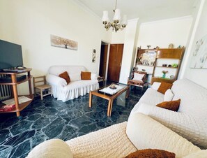 A living room with a sofa, armchair, coffee table, and a TV stand. - Altana Vista Argolis - Panoramic Castle View (Argos)