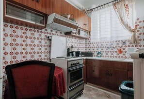 A compact kitchen with a refrigerator, stove, microwave, and wooden cabinets. - Altana Vista Argolis - Panoramic Castle View (Argos)