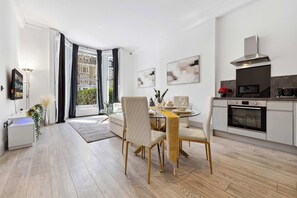 Une cuisine moderne dotée d’un four encastré et d’un coin repas avec une table et des chaises en verre.