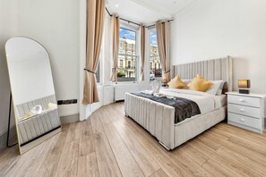 A modern bedroom with a large bed, bedside tables, a mirror, and a view of the city. - VIRAL Kensignton 2BR Refreshing Dream Home by Station for 6 (Greater London)