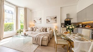 Een moderne woonkamer met een glazen salontafel, een beige bank en een eethoek met een glazen tafel gedekt voor het ontbijt.