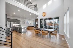 A spacious kitchen with modern appliances, a dining area with wooden chairs, and a staircase leading to a loft. - Hot Tub + Fire Pit | Trails + Park City Mtns | Poppy & Pine (Park City)