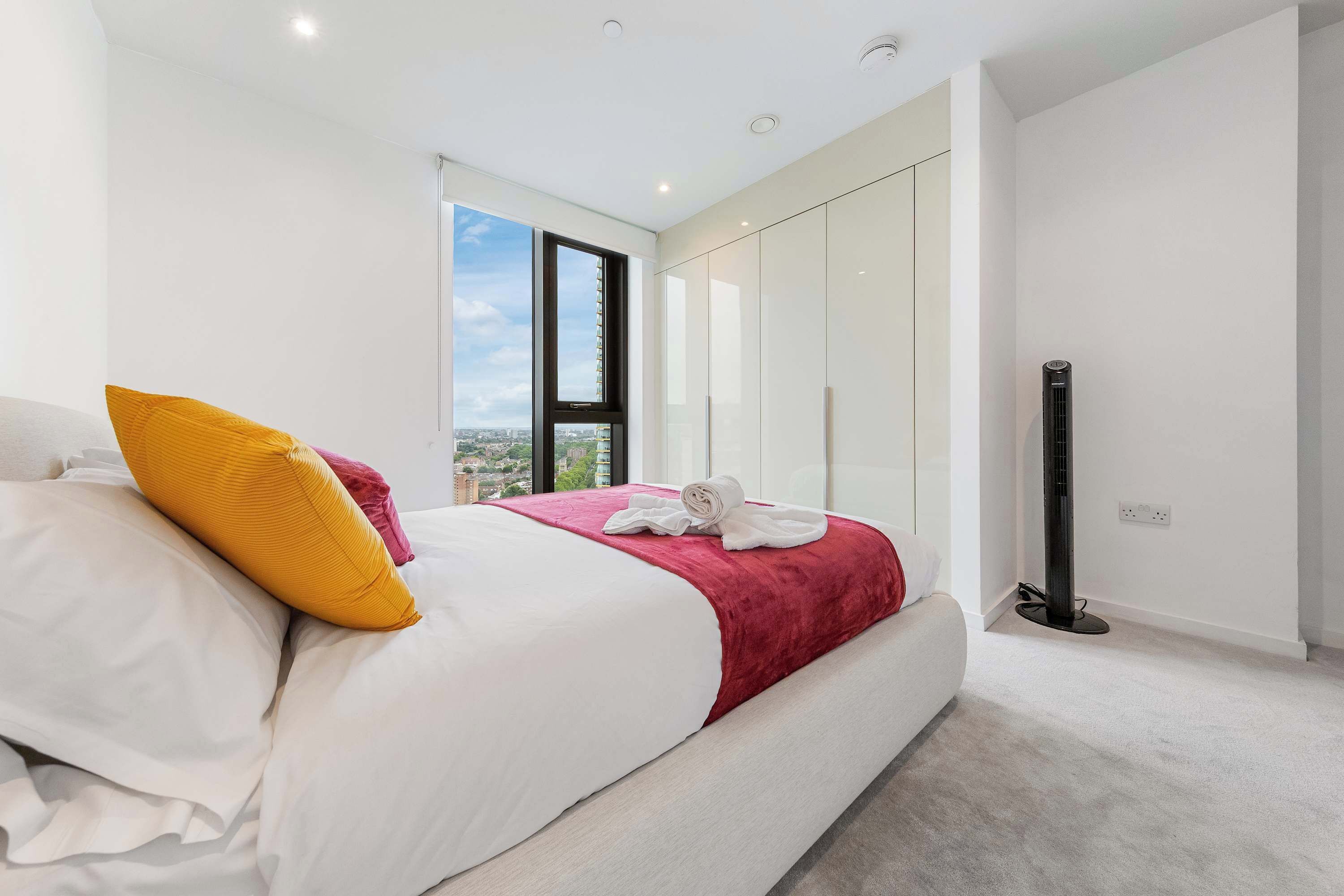 A modern bedroom with a large bed, a view of the city, and a standing heater.