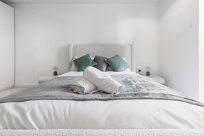 Une chambre à coucher au style minimaliste, avec un lit, des oreillers et des lampes de chevet.