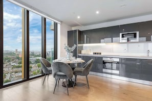 A modern kitchen with a large window, a dining table with chairs, and Bosch appliances. - Tik Tok Famous Skyline Apartment 2BR Memories London, One of London's Most Exclusive Stays (Greater London)