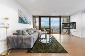 Un salon moderne avec un canapé gris, une table basse en verre et un tapis vert.