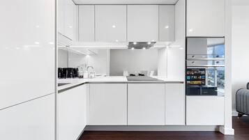 A modern kitchen with white cabinetry, a built-in oven, and a refrigerator with a digital display.