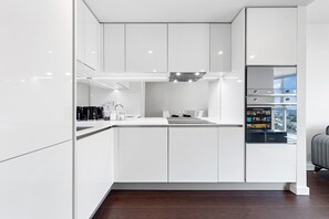 Eine moderne Küche mit weißen Schränken, einem eingebauten Backofen und einem Kühlschrank mit digitaler Anzeige.