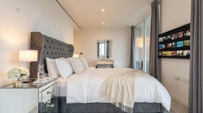 A modern bedroom with a large bed, a bedside table, a mirror, and a TV mounted on the wall displaying movie posters. - ELEVATED SHARD VIEW PANORAMIC SECRET STAY, Top Floor Penthouse, Gym and Rooftop (Greater London)