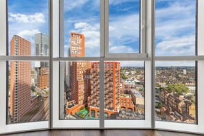 Une grande fenêtre à carreaux multiples offrant une vue sur les gratte-ciel et le paysage urbain.