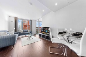 Ein modernes Wohnzimmer mit Sofa, Couchtisch und Fernseher. Ein Essbereich mit Tisch für zwei Personen.