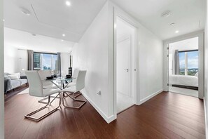Ein modernes Wohnzimmer mit einem Glastisch, weißen Sofas und Blick auf die Stadt.