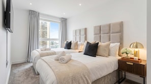 A hotel room with two beds, a large window with curtains, a flat-screen TV, a bedside table with a lamp, and a view of the cityscape. - INSTAGRAM VIRAL SKY HIGH SANCTUARY With Gym and Exclusive Rooftop, Floor to Ceiling Windows (London)