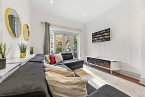 A modern living room with a sectional sofa, a flat-screen TV, and a fireplace.