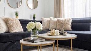 A modern living room with a dark sofa, round coffee table, and decorative items. - Notting Hill Neighbour - 2BR Designer Stay (Greater London)