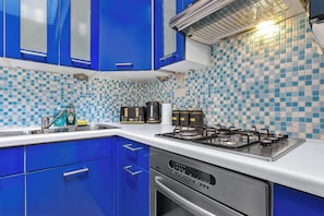 A kitchen with blue cabinets, a gas stove, and a tiled backsplash. - Dream Open-View Balcony Apartment for 6 Guests, Moments from Harrods for Beautiful London Nights (Greater London)