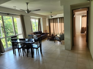 Amplia sala de estar con una mesa de comedor, sillas, sofás y ventiladores de techo.