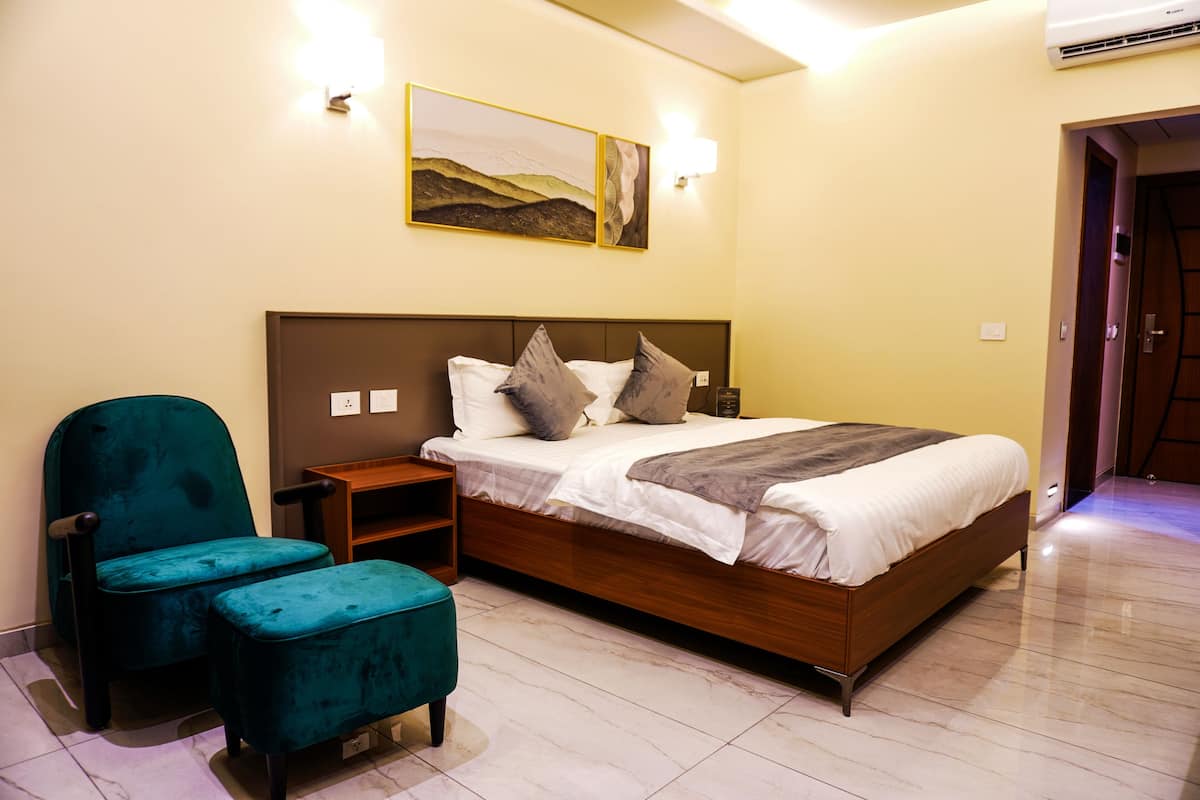 Une chambre à coucher avec un lit, une chaise, une table de chevet et un tableau au mur.