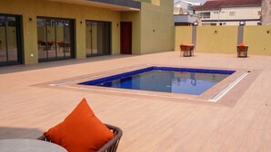 An outdoor swimming pool with a tiled edge, surrounded by a wooden deck. - HOTEL PANORAMA (Kinshasa)