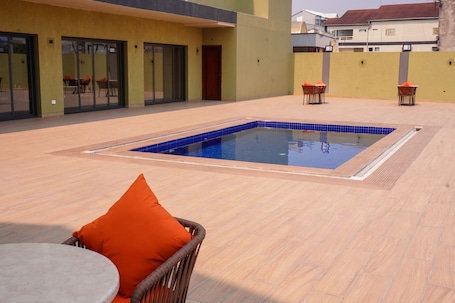 An outdoor swimming pool with a tiled edge, surrounded by a wooden deck.. HOTEL PANORAMA