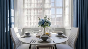 Mesa de jantar posta para quatro pessoas, com um vaso de flores, pratos, tigelas e talheres.