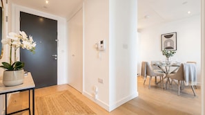 A modern interior with a dining area, a potted orchid, and a black door. - London Skyline 1BR with Rooftop, Gym & Shard Views (Greater London)