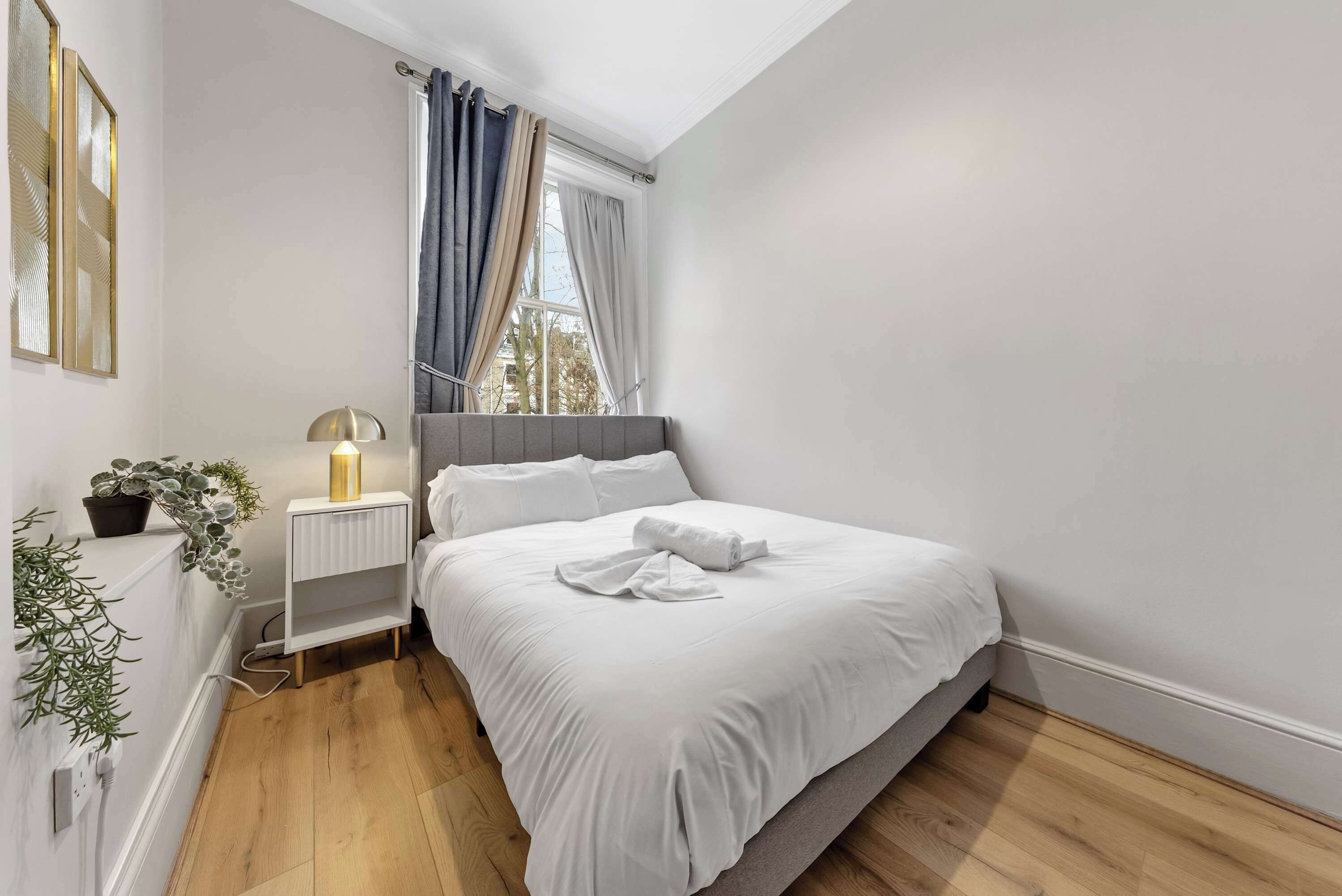 A bedroom with a bed, bedside lamp, and a window with curtains.