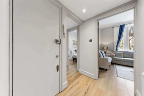 Un pasillo que conduce a una sala de estar con un sofá y una lámpara.