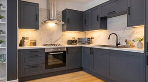 Een moderne keuken met donkere kastjes, een gasfornuis, een magnetron en een spoelbak.