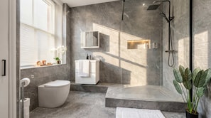 Ein modernes Badezimmer mit Dusche, Toilette, Waschbecken und einem großen Spiegel.