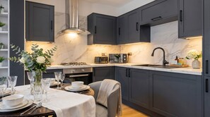 Een moderne keuken met donkere kastjes, een gasfornuis, een magnetron en een spoelbak.