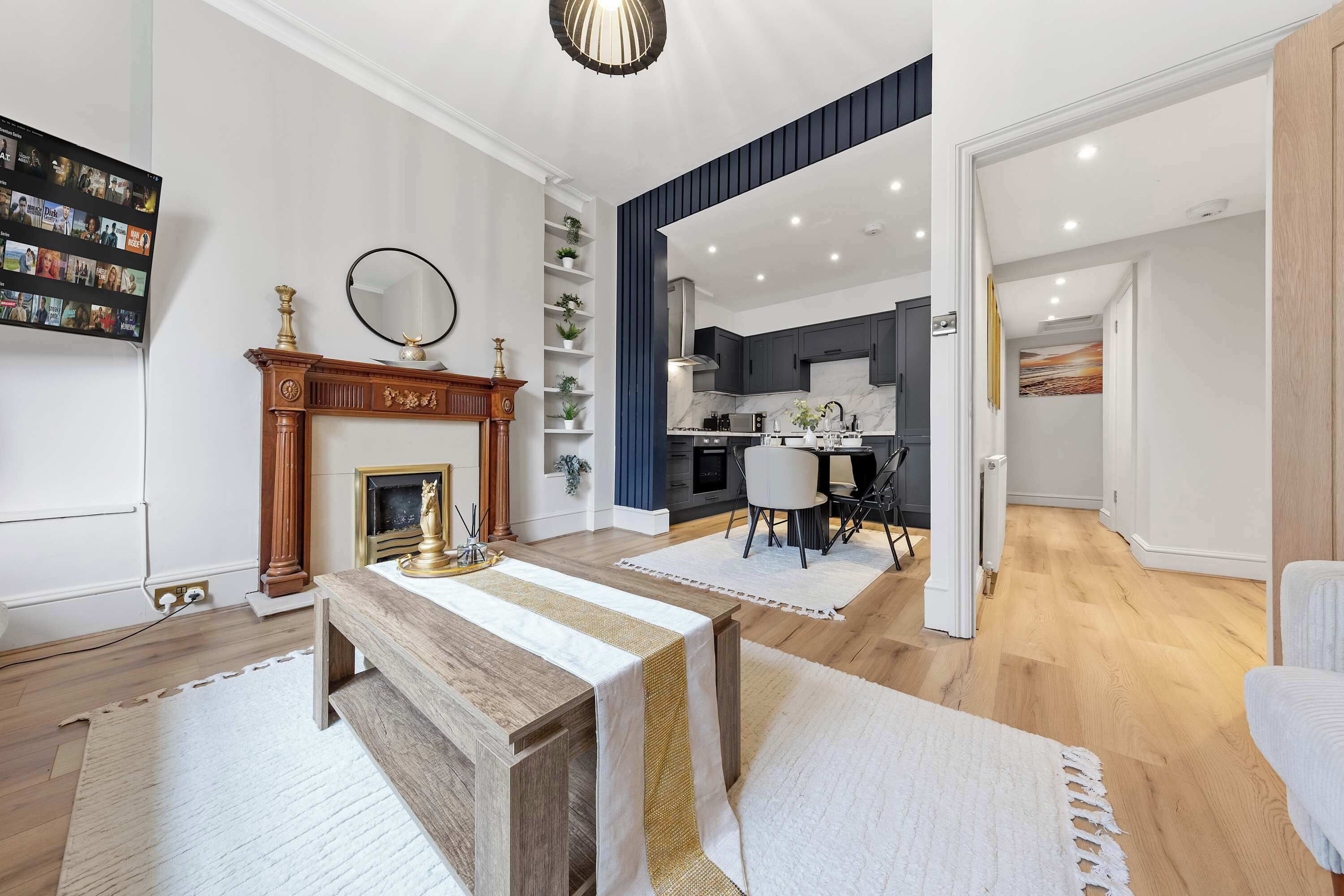 A modern living room with a fireplace, a dining area, and a kitchen.